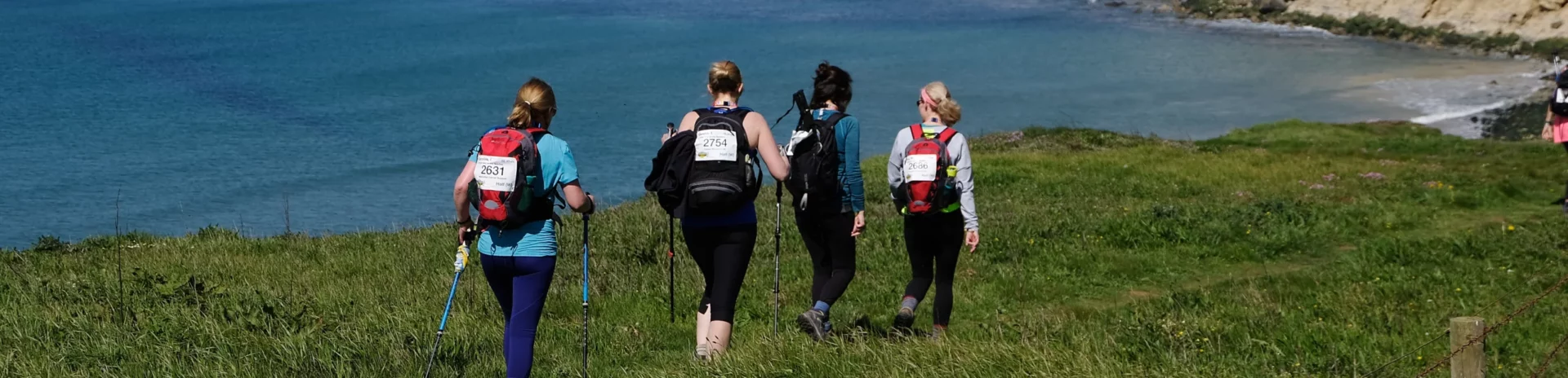 four people walking along the coast line of Isle of Wight, sea in the distance