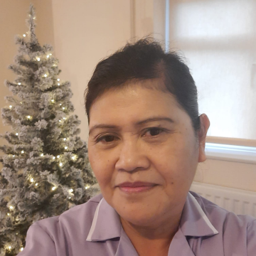 A photo of Foothold community member Imelda, smiling in front of a Christmas tree