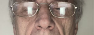 A close-up photograph of Brian, who is wearing glasses and looking towards the camera.