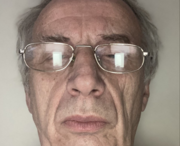 A close-up photograph of Brian, who is wearing glasses and looking towards the camera.