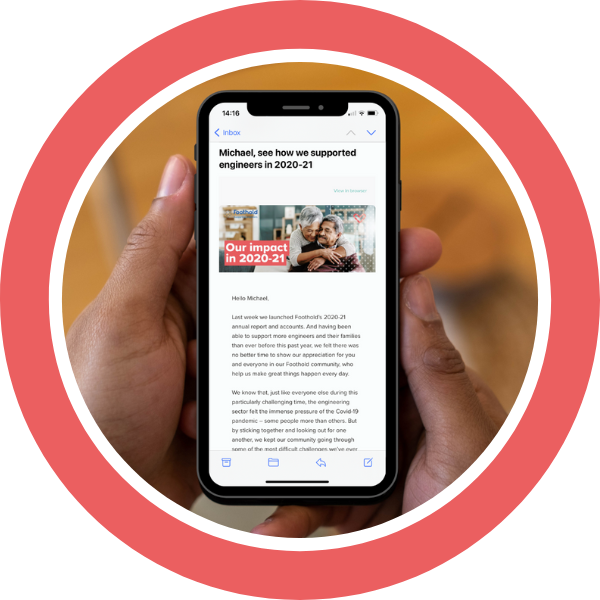 An image showing someone's hands holding a mobile phone. The phone is displaying a version of the Foothold monthly newsletter.