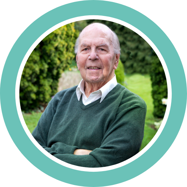 David Branded A photograph of an old man, slightly smiling and looking towards the camera. He is standing in a garden wearing a white shirt and green jumper. Representing IET community member David.