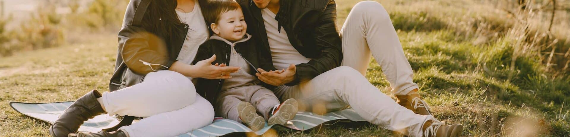 Two parents and a baby having a picnic in a field